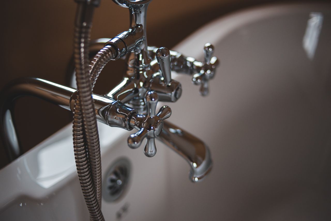 hero-img-02 Elegant close-up of a shiny chrome faucet in a modern bathroom setting.