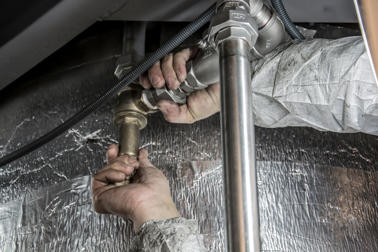 about-01 Close-up of a plumber's hands installing steel pipes indoors, showcasing skilled manual work.